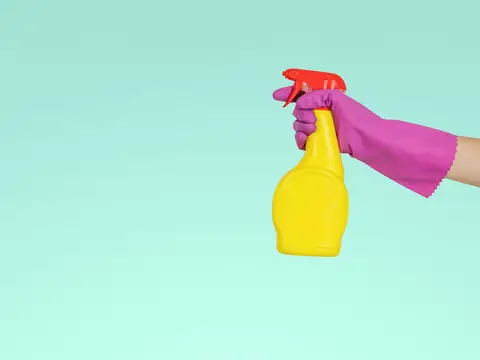 Gloved hand holding a spray bottle of cleaner