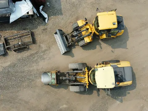 Aerial view of two yellow construction machines on a gravel site